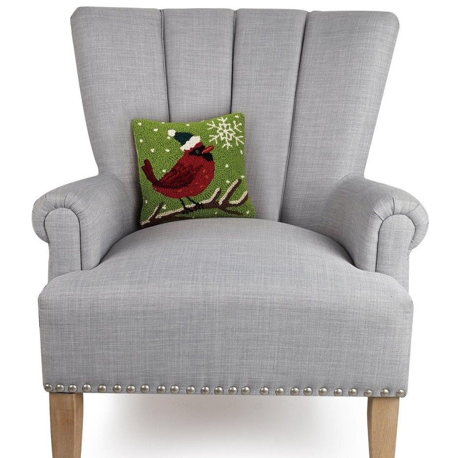Cardinal with Snowflake Hooked Wool Christmas Throw Pillow on an armchair, showing the throw pillow at room scale, 10x10 inch