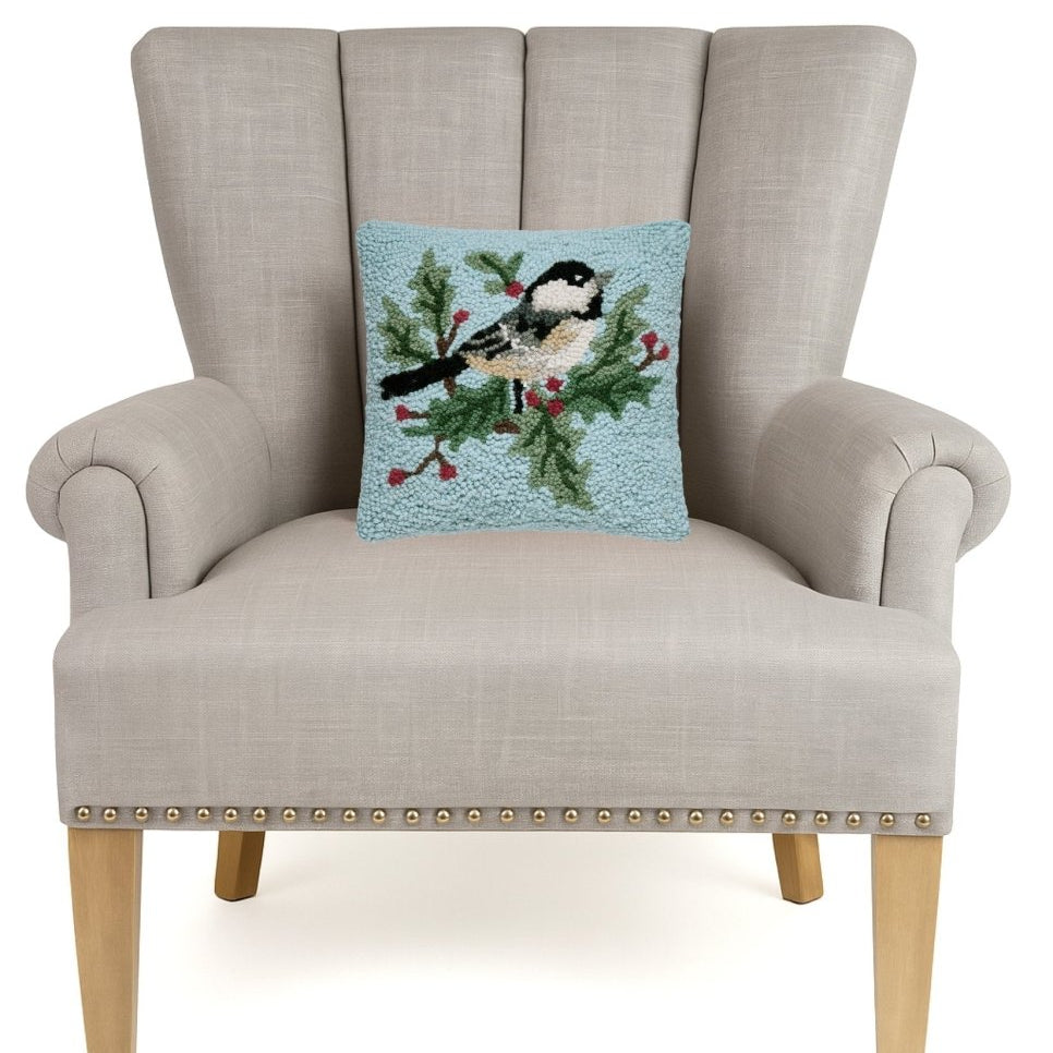 Chickadee Holly Hooked Wool Christmas Throw Pillow on an armchair, showing the throw pillow at room scale, 10x10 inch
