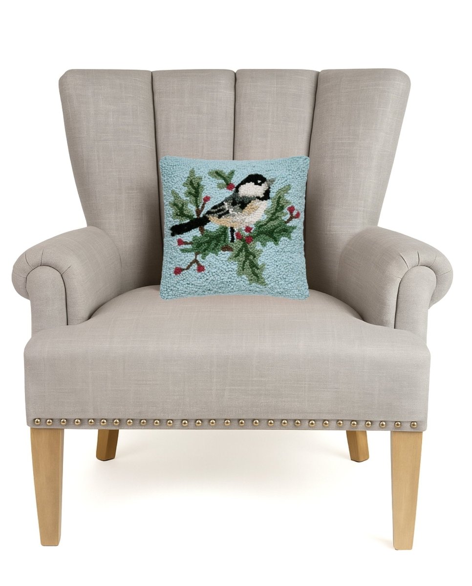 Chickadee Holly Hooked Wool Christmas Throw Pillow on an armchair, showing the throw pillow at room scale, 10x10 inch