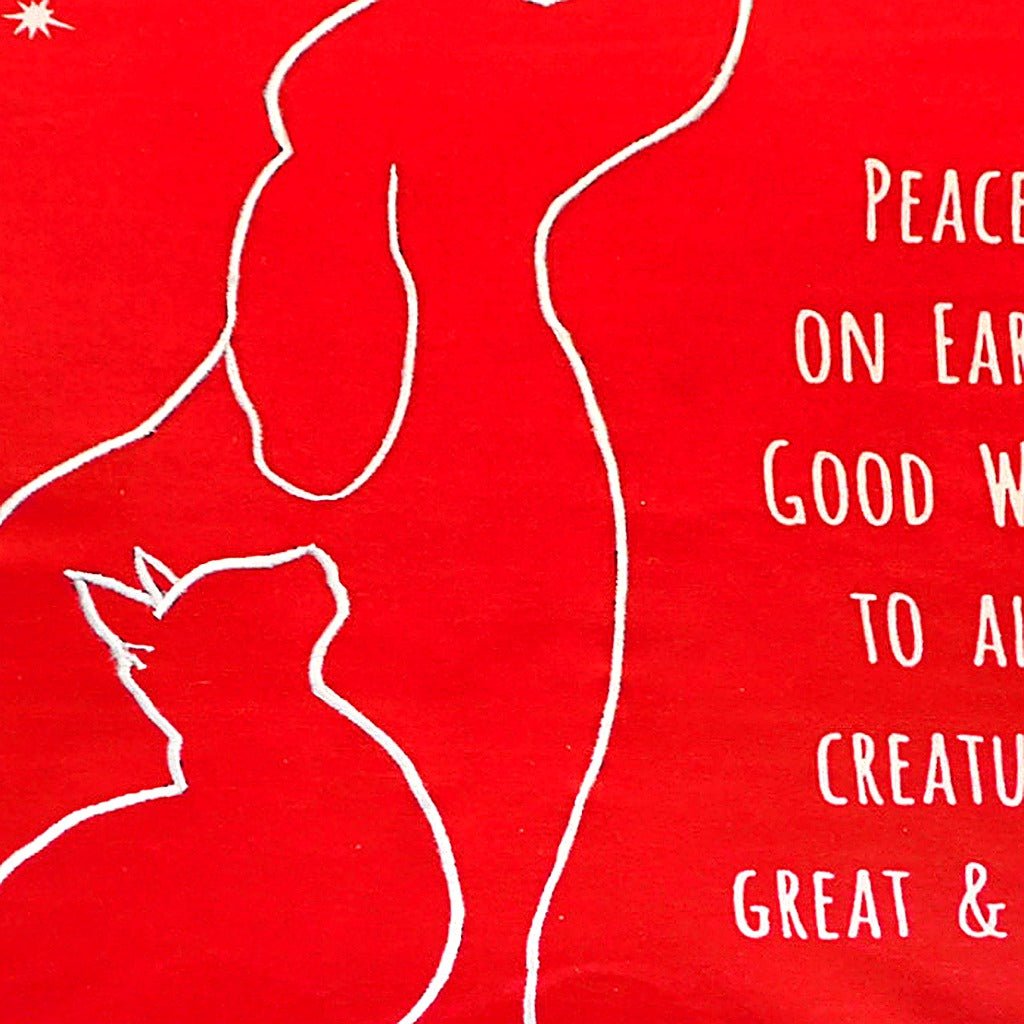 Closeup of Christmas Peace On Earth Dog needlepoint throw pillow highlighting hand-stitched wool craftsmanship and fabric detail