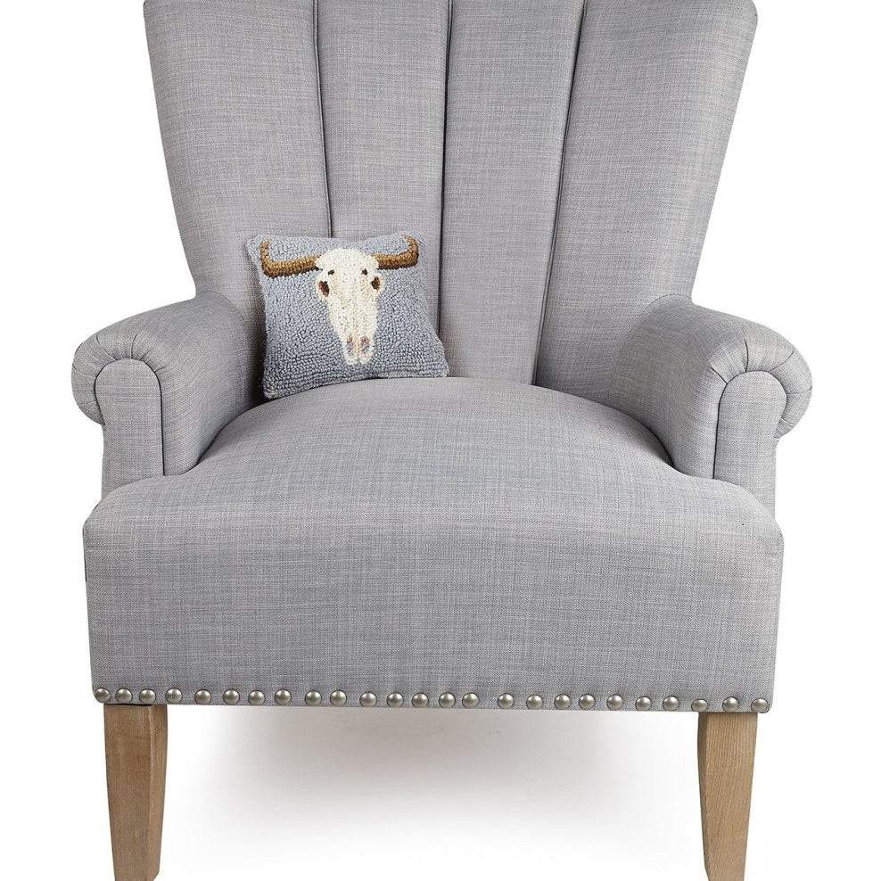 Cow Skull Hooked Wool Halloween Throw Pillow on an armchair, showing the throw pillow at room scale, 8x18 inch