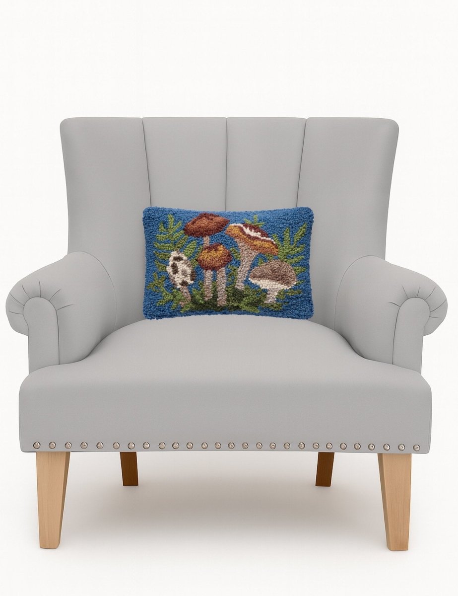 Forest Floor Mushrooms Hooked Wool Throw Pillow on an armchair, showing the throw pillow at room scale, 8x12 inch