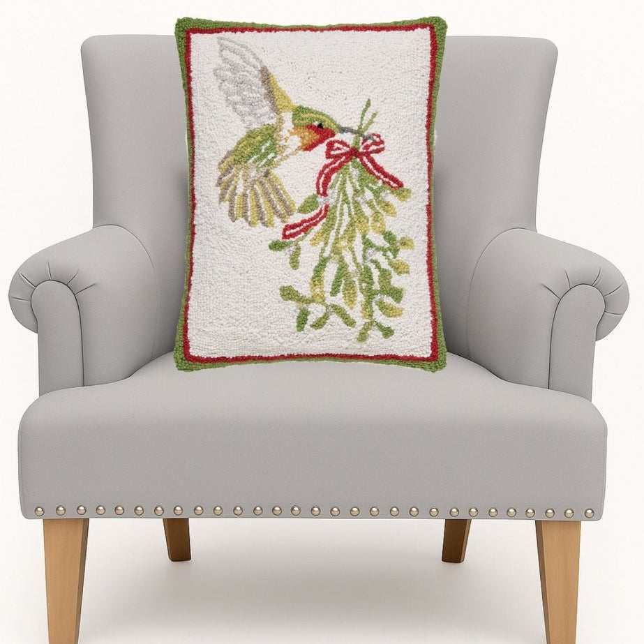 Hummingbird Mistletoe Hooked Wool Christmas Throw Pillow on an armchair, showing the throw pillow at room scale, 14x18 inch