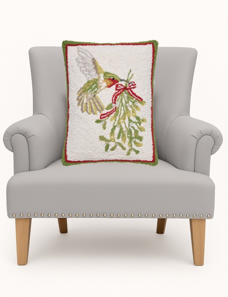 Hummingbird Mistletoe Hooked Wool Christmas Throw Pillow on an armchair, showing the throw pillow at room scale, 14x18 inch