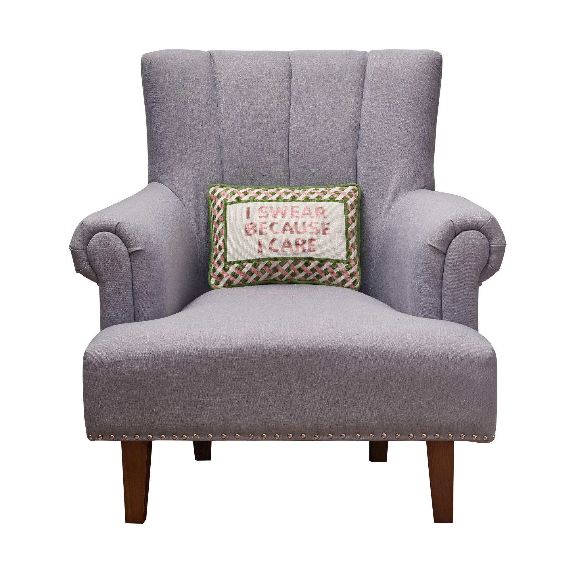 I Swear Because I Care Embroidered Needlepoint Throw Pillow, 10x14 inch, propped on a gray upholstered armchair