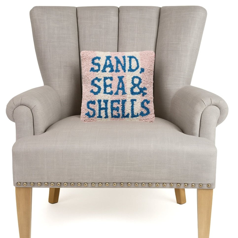 Sand Sea & Shells Hooked Wool Throw Pillow on an armchair, showing the throw pillow at room scale, 10x10 inch