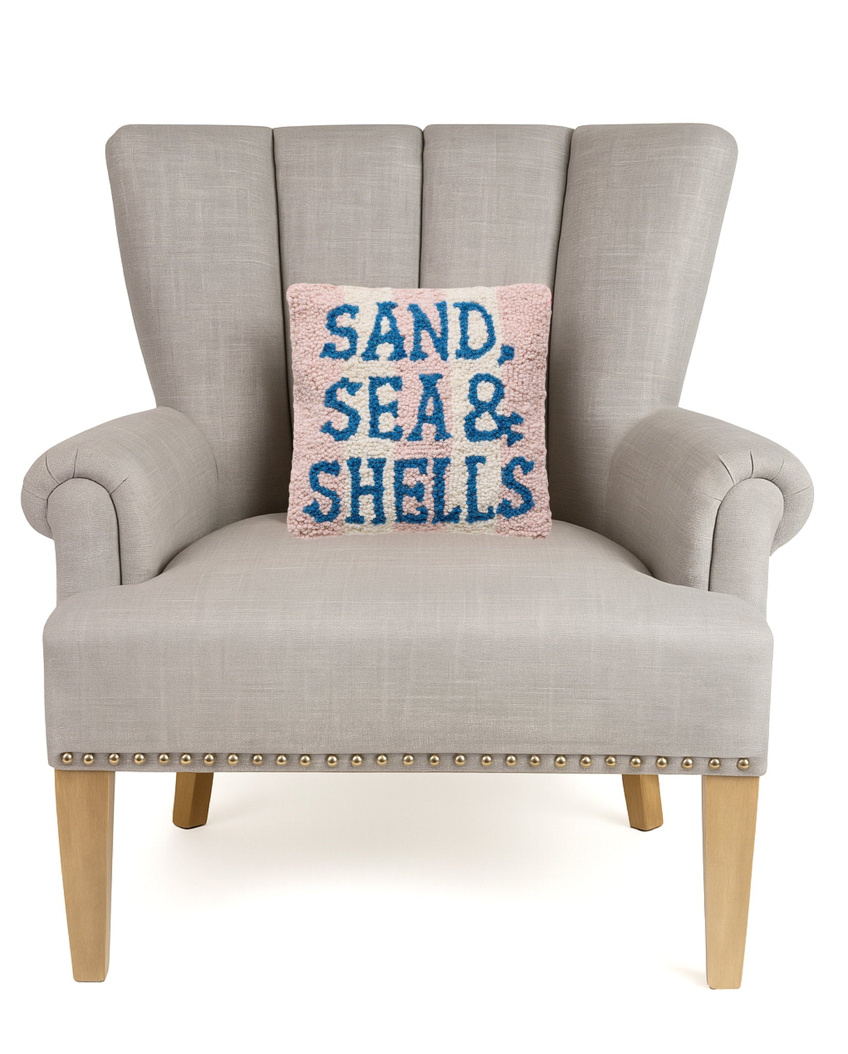 Sand Sea & Shells Hooked Wool Throw Pillow on an armchair, showing the throw pillow at room scale, 10x10 inch