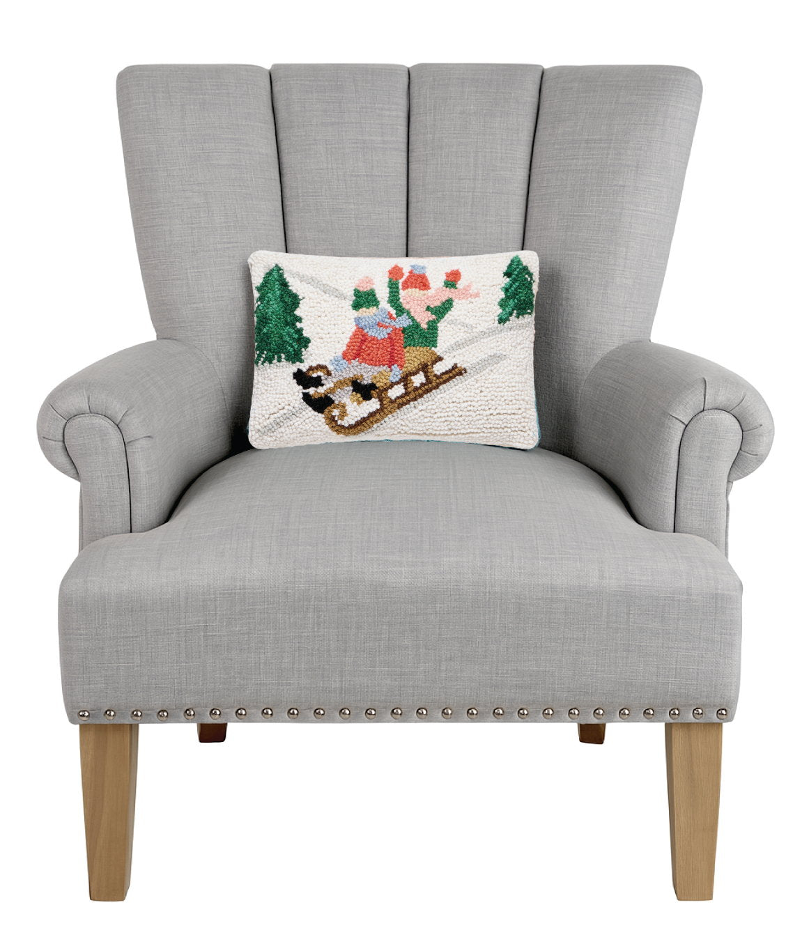 Sledding Kids Hooked Wool Christmas Throw Pillow on an armchair, showing the throw pillow at room scale, 8x12 inch