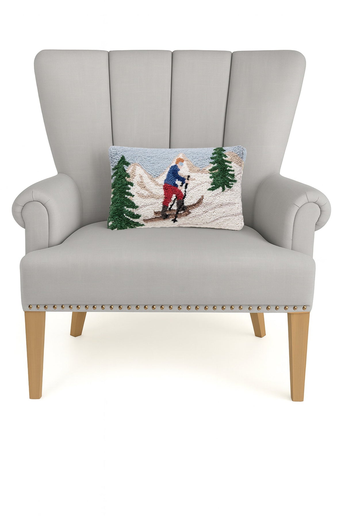 Uphill Skier Hooked Wool Christmas Throw Pillow on an armchair, showing the throw pillow at room scale, 8x12 inch