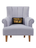 Black and Gold Trick or Treat Hooked Wool Halloween Throw Pillow on an armchair, showing the throw pillow at room scale, 8x12 inch