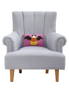 Candy Bat Hooked Wool Halloween Throw Pillow on an armchair, showing the throw pillow at room scale, 8x12 inch
