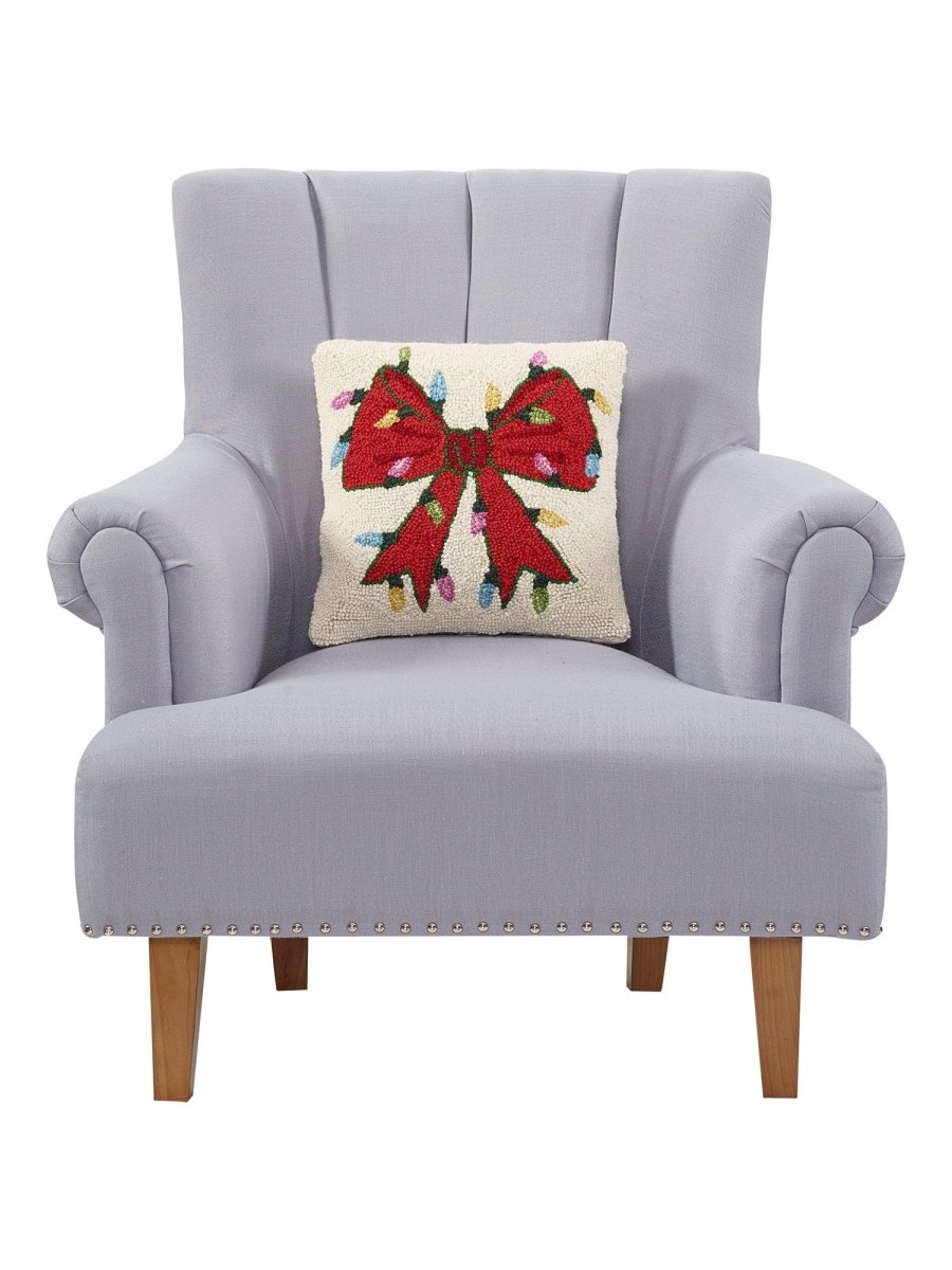 Christmas Lights Bow Hooked Wool Throw Pillow on an armchair, showing the throw pillow at room scale, 14x14 inch