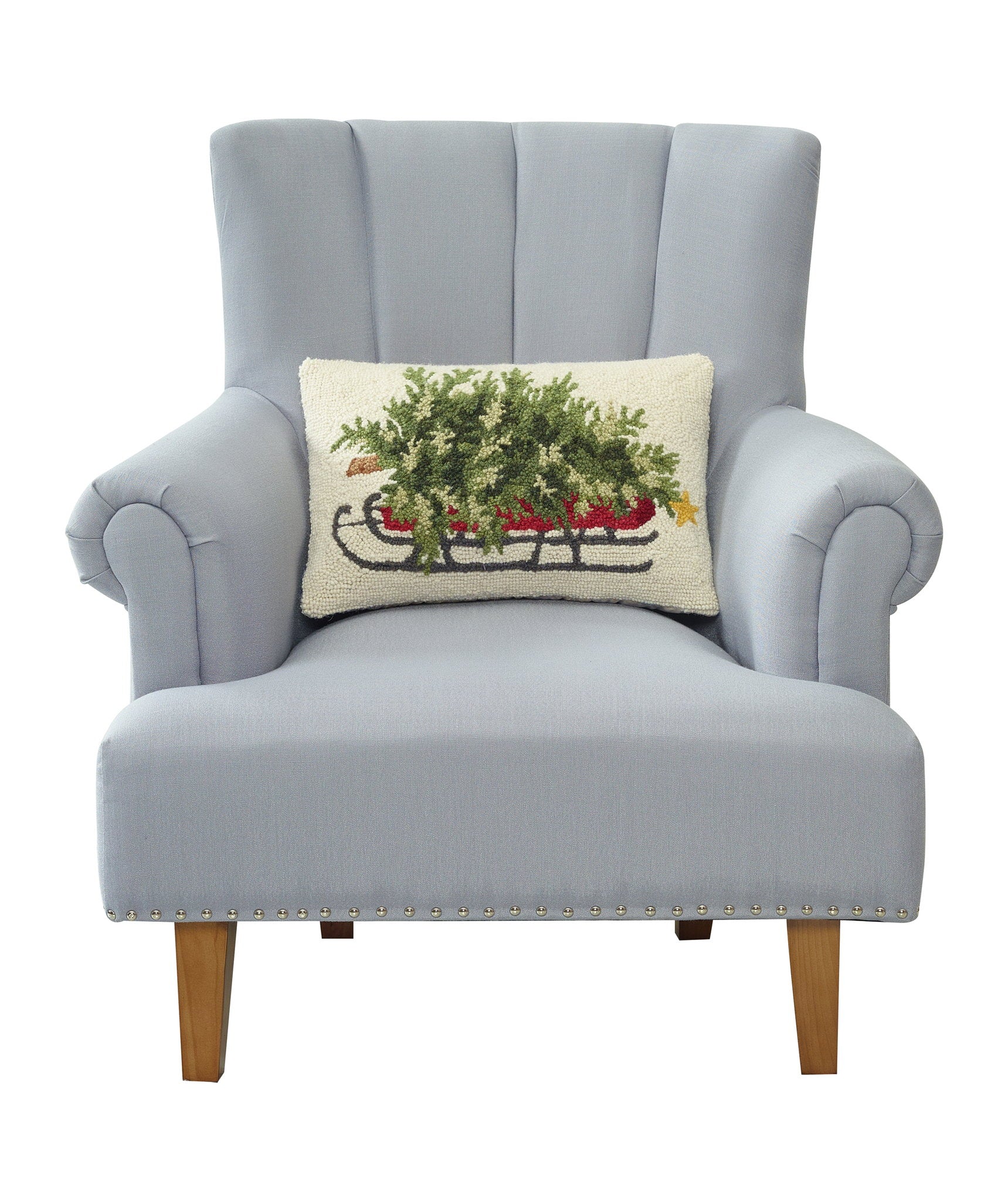 Christmas Tree on Sled Hooked Wool Throw Pillow on an armchair, showing the throw pillow at room scale, 12x18 inch