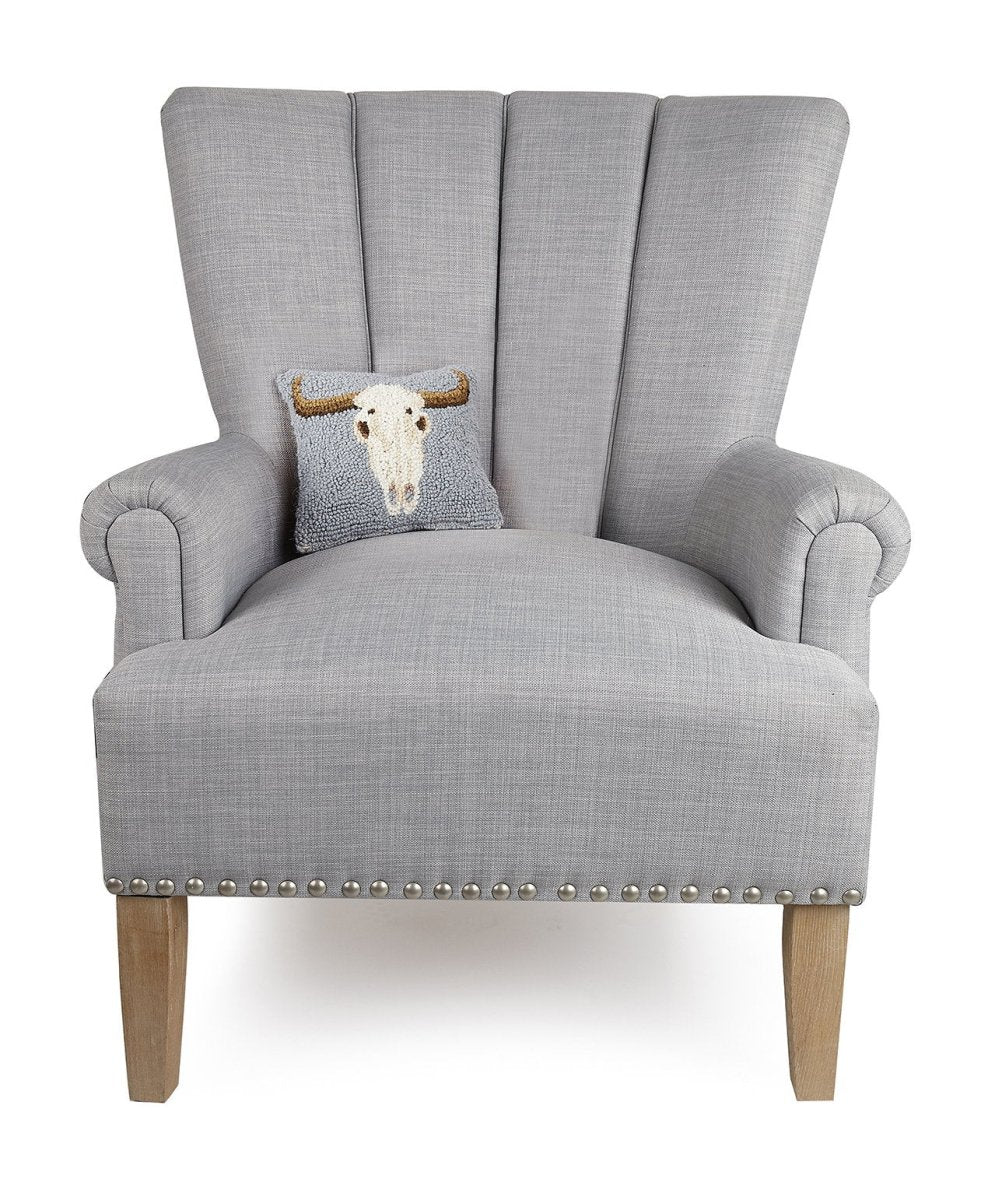 Cow Skull Hooked Wool Halloween Throw Pillow on an armchair, showing the throw pillow at room scale, 8x18 inch