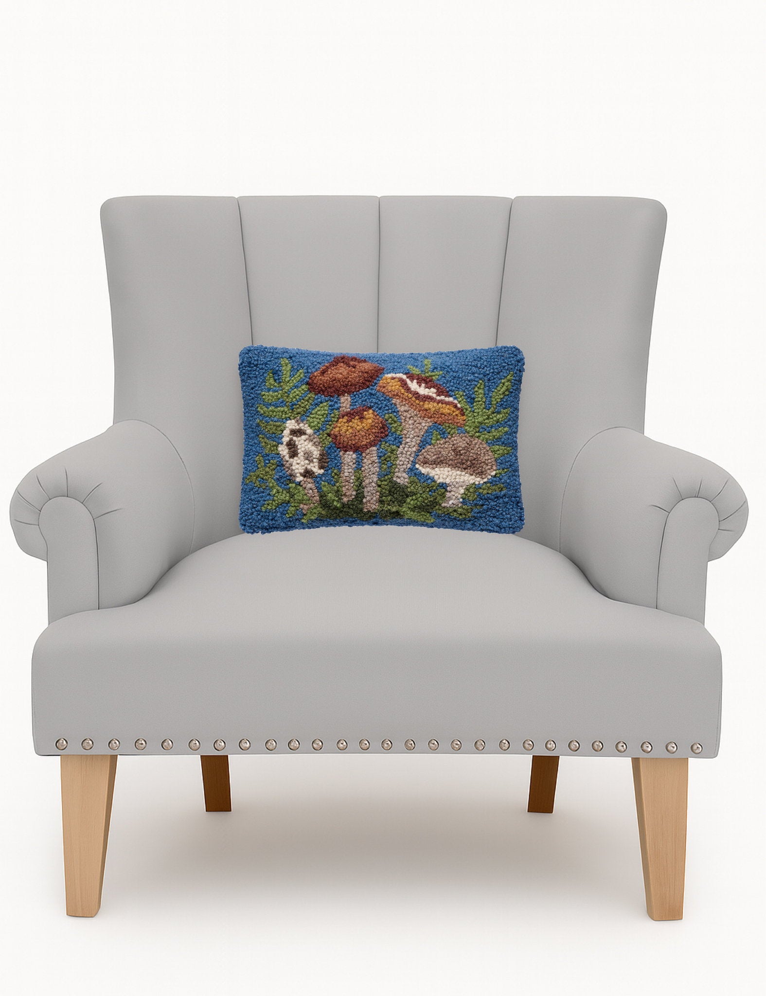 Forest Floor Mushrooms Hooked Wool Throw Pillow on an armchair, showing the throw pillow at room scale, 8x12 inch