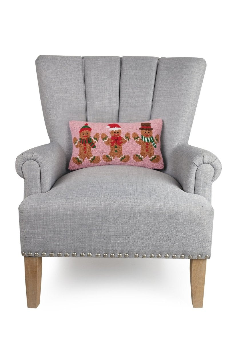 Gingerbreads Group Three Hooked Wool Christmas Throw Pillow on an armchair, showing the throw pillow at room scale, 9x16 inch