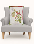 Hummingbird Mistletoe Hooked Wool Christmas Throw Pillow on an armchair, showing the throw pillow at room scale, 14x18 inch