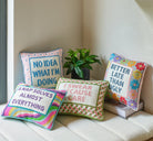 I Swear Because I Care Embroidered Needlepoint Throw Pillow, 10x14 inch, five word pillows on a white bench with a plant