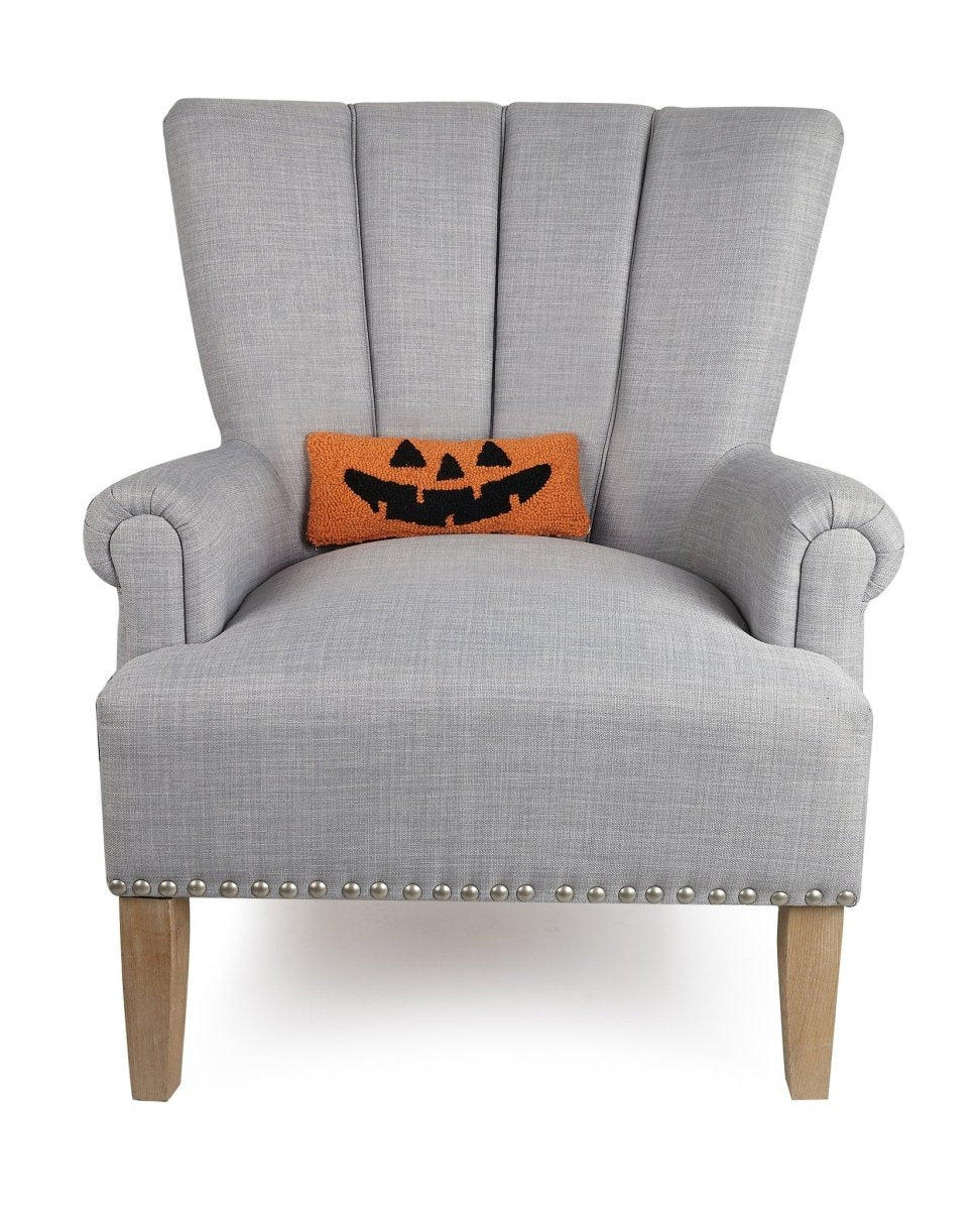 Jack-O-Lantern Hooked Wool Halloween Throw Pillow on an armchair, showing the throw pillow at room scale, 12x5 inch