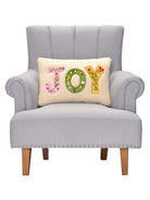 Joy Applique Embroidered Christmas Throw Pillow on an armchair, showing the throw pillow at room scale, 12x18 inch