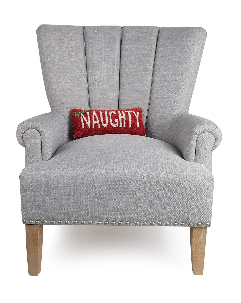 Naughty Hooked Wool Christmas Throw Pillow on an armchair, showing the throw pillow at room scale, 12x5 inch