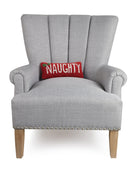 Naughty Hooked Wool Christmas Throw Pillow on an armchair, showing the throw pillow at room scale, 12x5 inch
