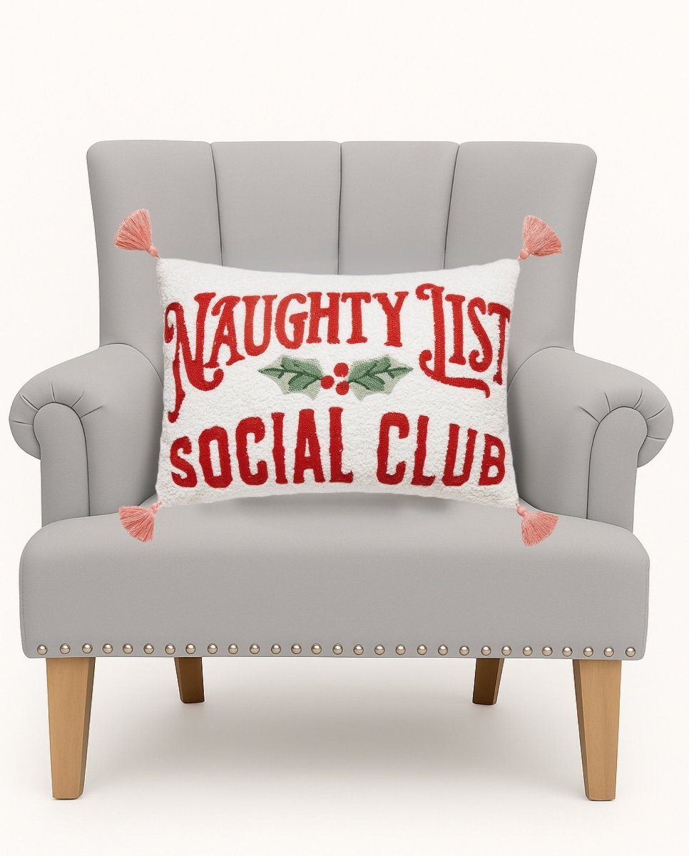 Naughty Social Club Embroidered Christmas Throw Pillow on an armchair, showing the throw pillow at room scale, 12x18 inch