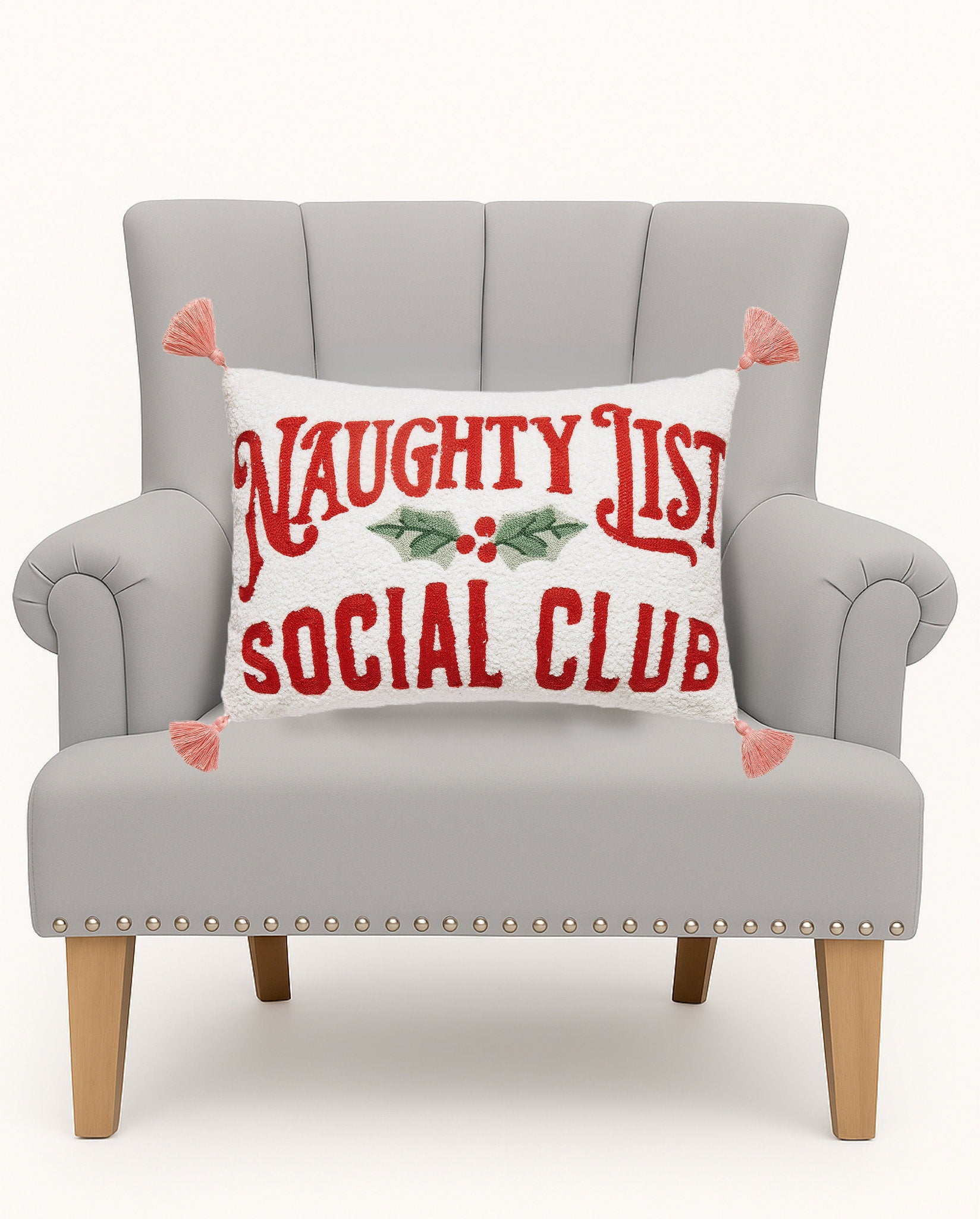 Naughty Social Club Embroidered Christmas Throw Pillow on an armchair, showing the throw pillow at room scale, 12x18 inch