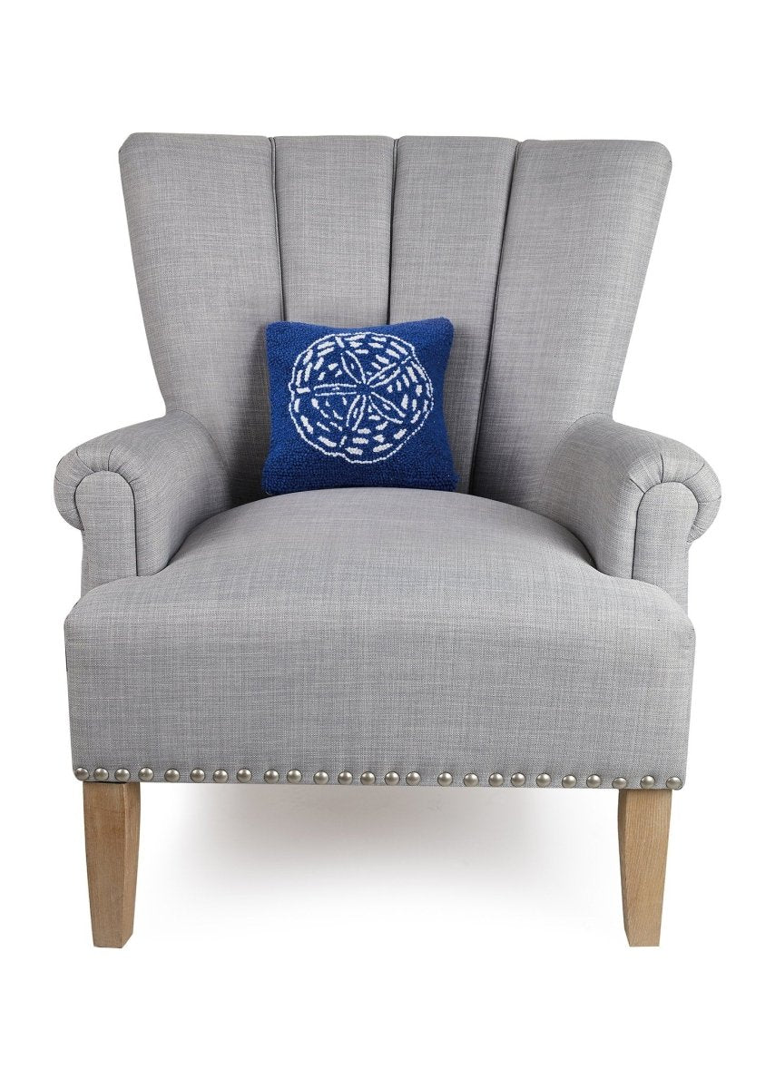 Navy Ground Sand Dollar Hooked Wool Throw Pillow on an armchair, showing the throw pillow at room scale, 10x10 inch