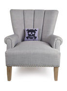 Pastel Skull Hooked Wool Halloween Throw Pillow on an armchair, showing the throw pillow at room scale, 8x8 inch
