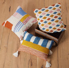 Percy Decorative Hooked Throw Pillow, 12x18 inch, four pillows around a wooden box on a plank floor