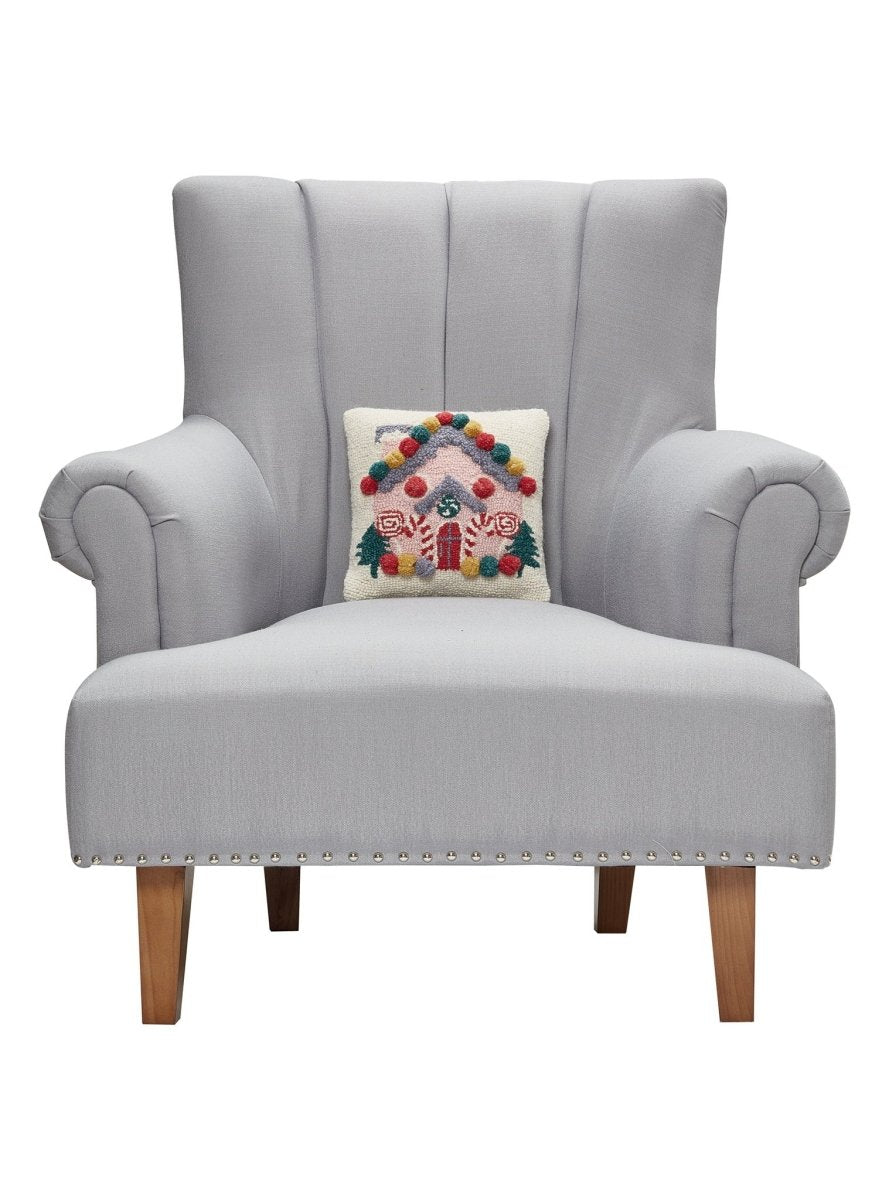 Pink House Hooked Wool Christmas Throw Pillow on an armchair, showing the throw pillow at room scale, 10x10 inch