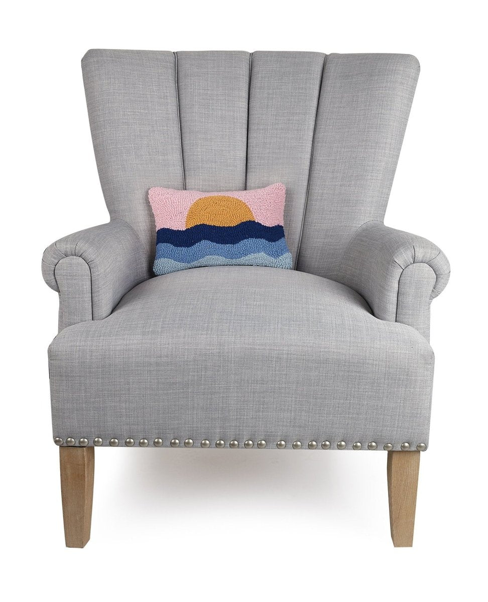 Pink Sky Coastal Sunset Hooked Wool Throw Pillow on an armchair, showing the throw pillow at room scale, 8x12 inch