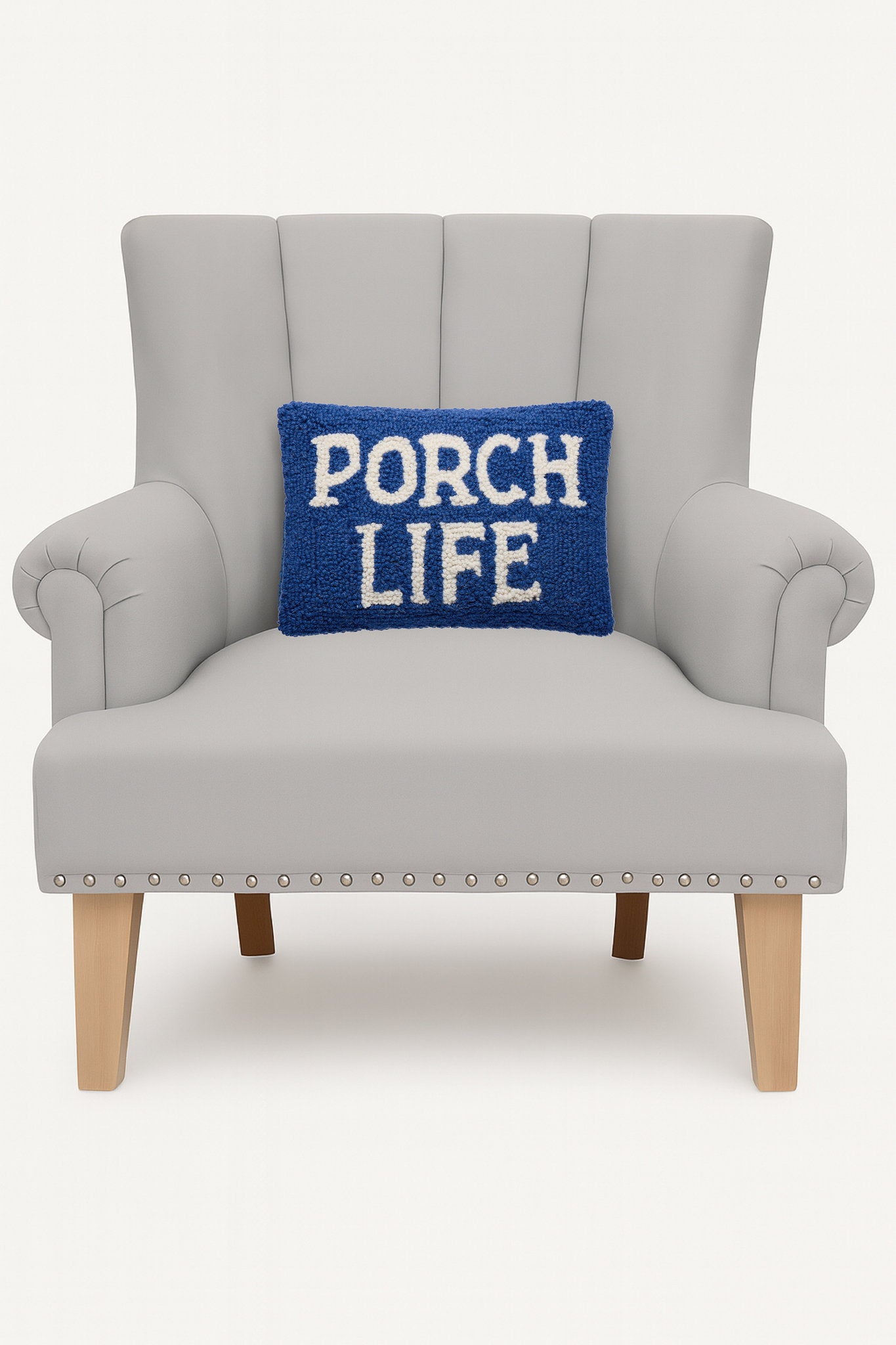 Porch Life Hooked Wool Throw Pillow on an armchair, showing the throw pillow at room scale, 8x12 inch