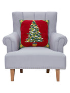 Red Ground Decorated Christmas Tree Hooked Wool Throw Pillow on an armchair, showing the throw pillow at room scale, 18x18 inch