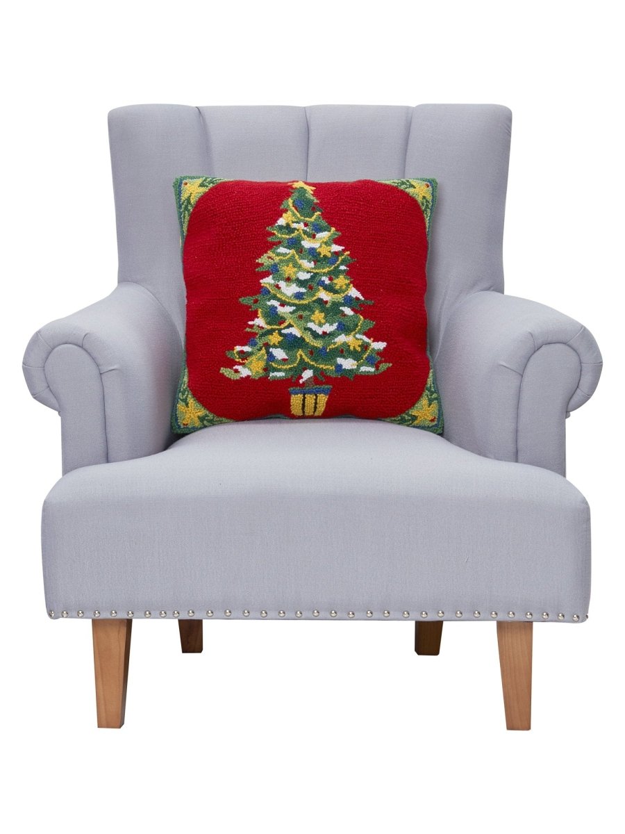 Red Ground Decorated Christmas Tree Hooked Wool Throw Pillow on an armchair, showing the throw pillow at room scale, 18x18 inch