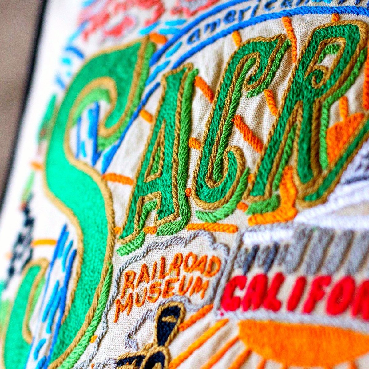 Sacramento, CA Gold Rush City Embroidered Travel Pillow - close-up detail of hand-embroidered needlepoint stitching