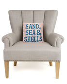 Sand Sea & Shells Hooked Wool Throw Pillow on an armchair, showing the throw pillow at room scale, 10x10 inch