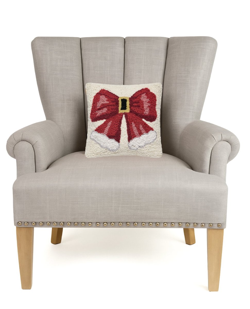 Santa Hat Bow Hooked Wool Christmas Throw Pillow on an armchair, showing the throw pillow at room scale, 10x10 inch