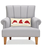 Santa Hat Trio Hooked Wool Christmas Throw Pillow on an armchair, showing the throw pillow at room scale, 8x20 inch