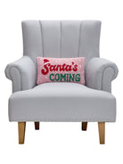 Santa's Coming Hooked Wool Christmas Throw Pillow on an armchair, showing the throw pillow at room scale, 9x16 inch
