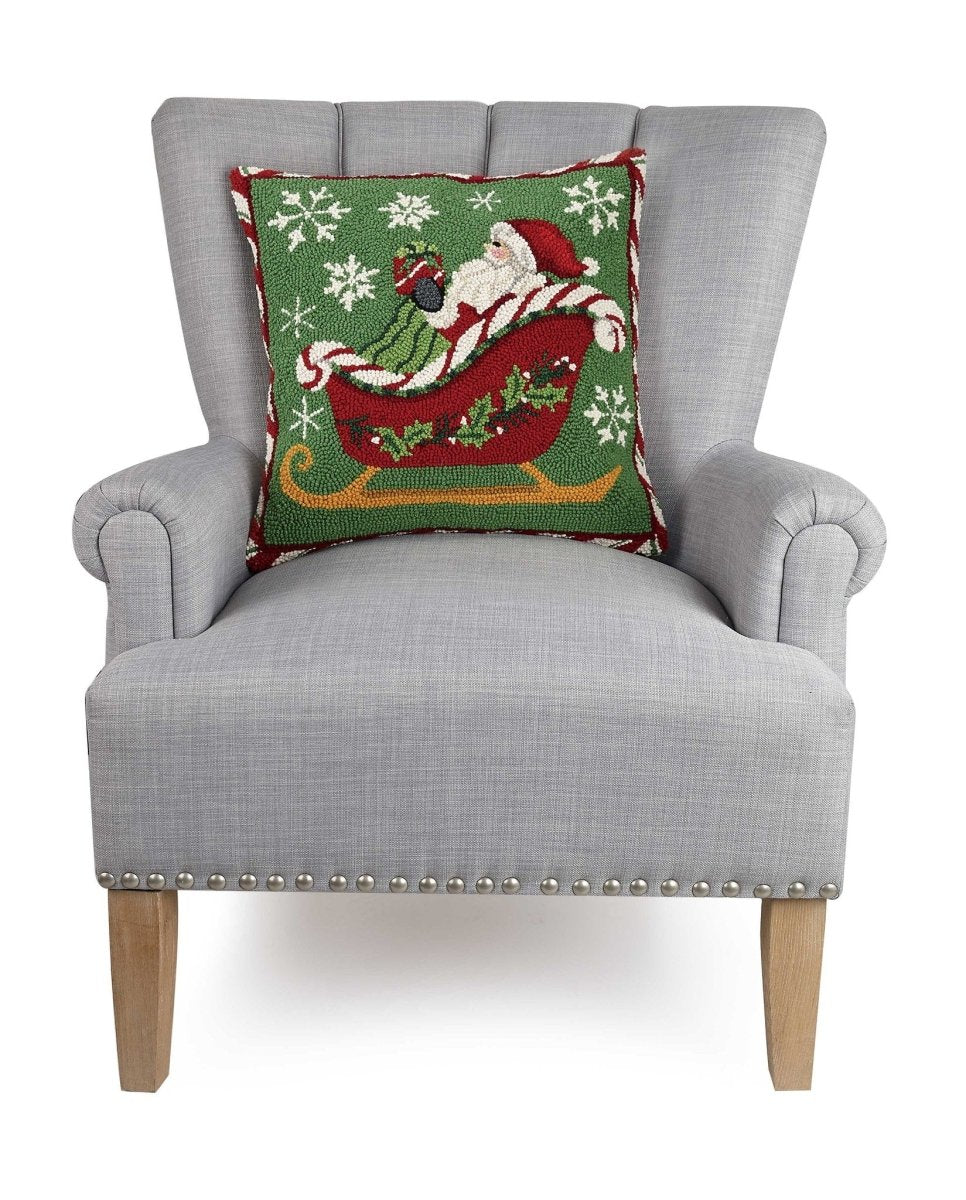 Santa Sleigh Hooked Wool Christmas Throw Pillow on an armchair, showing the throw pillow at room scale, 18x18 inch