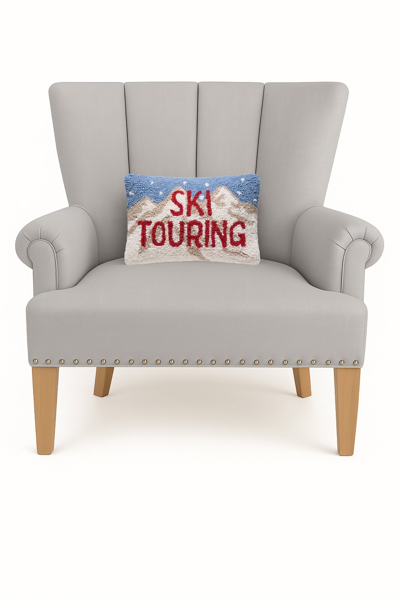 Ski Touring Hooked Wool Christmas Throw Pillow on an armchair, showing the throw pillow at room scale, 8x12 inch