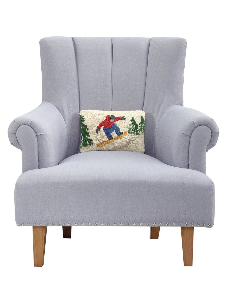 Snowboarder Hooked Wool Christmas Throw Pillow on an armchair, showing the throw pillow at room scale, 8x12 inch