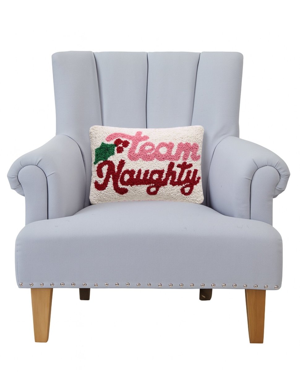 Team Naughty Hooked Wool Christmas Throw Pillow on an armchair, showing the throw pillow at room scale, 8x12 inch