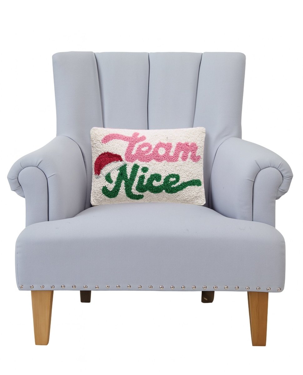 Team Nice Hooked Wool Christmas Throw Pillow on an armchair, showing the throw pillow at room scale, 8x12 inch