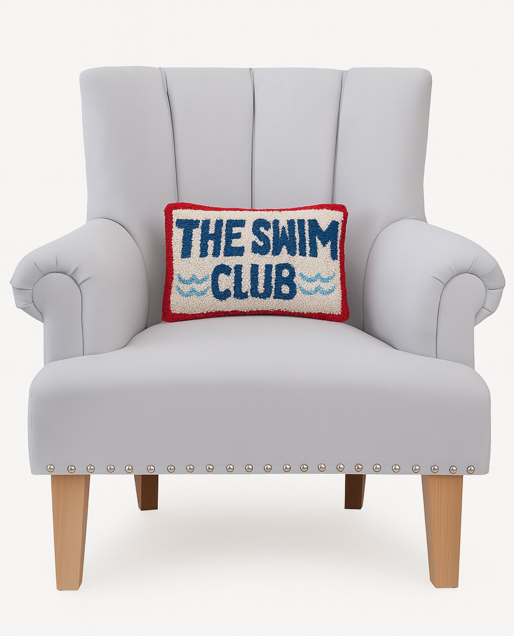 The Swim Club Hooked Wool Throw Pillow on an armchair, showing the throw pillow at room scale, 8x12 inch