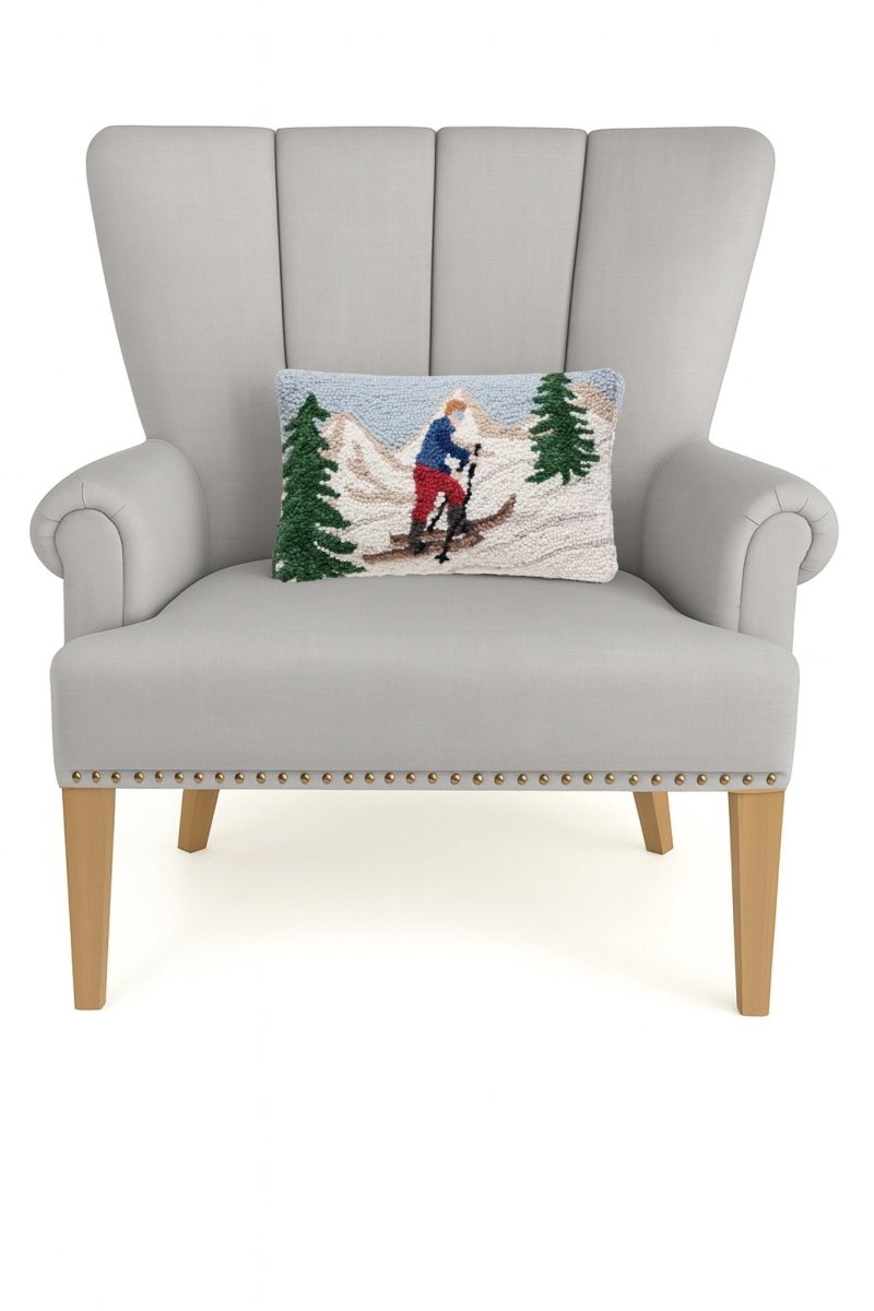 Uphill Skier Hooked Wool Christmas Throw Pillow on an armchair, showing the throw pillow at room scale, 8x12 inch