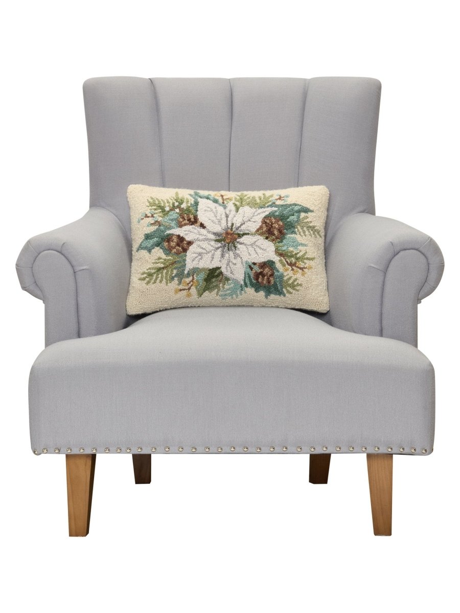 White Poinsettia with Pinecones Hooked Wool Christmas Throw Pillow on an armchair, showing the throw pillow at room scale, 12x18 inch