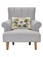 White Poinsettia with Pinecones Hooked Wool Christmas Throw Pillow on an armchair, showing the throw pillow at room scale, 12x18 inch